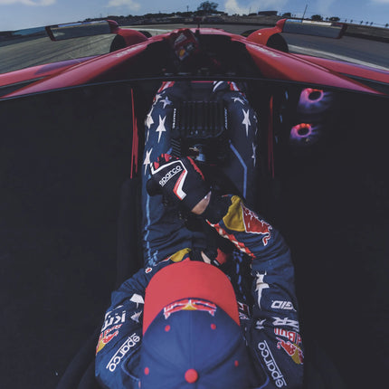 Racing driver in simulator wearing black and red gloves.