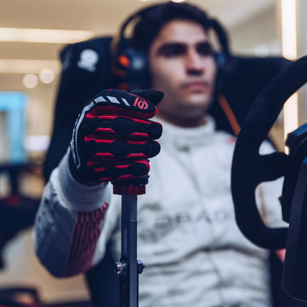 Person using black and red racing gloves in a sim racing setup.